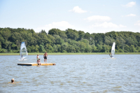 Windsurfers and bathing campers at the lake