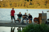 The youth is singing and playing guitar and drums on the raft at the beach concert